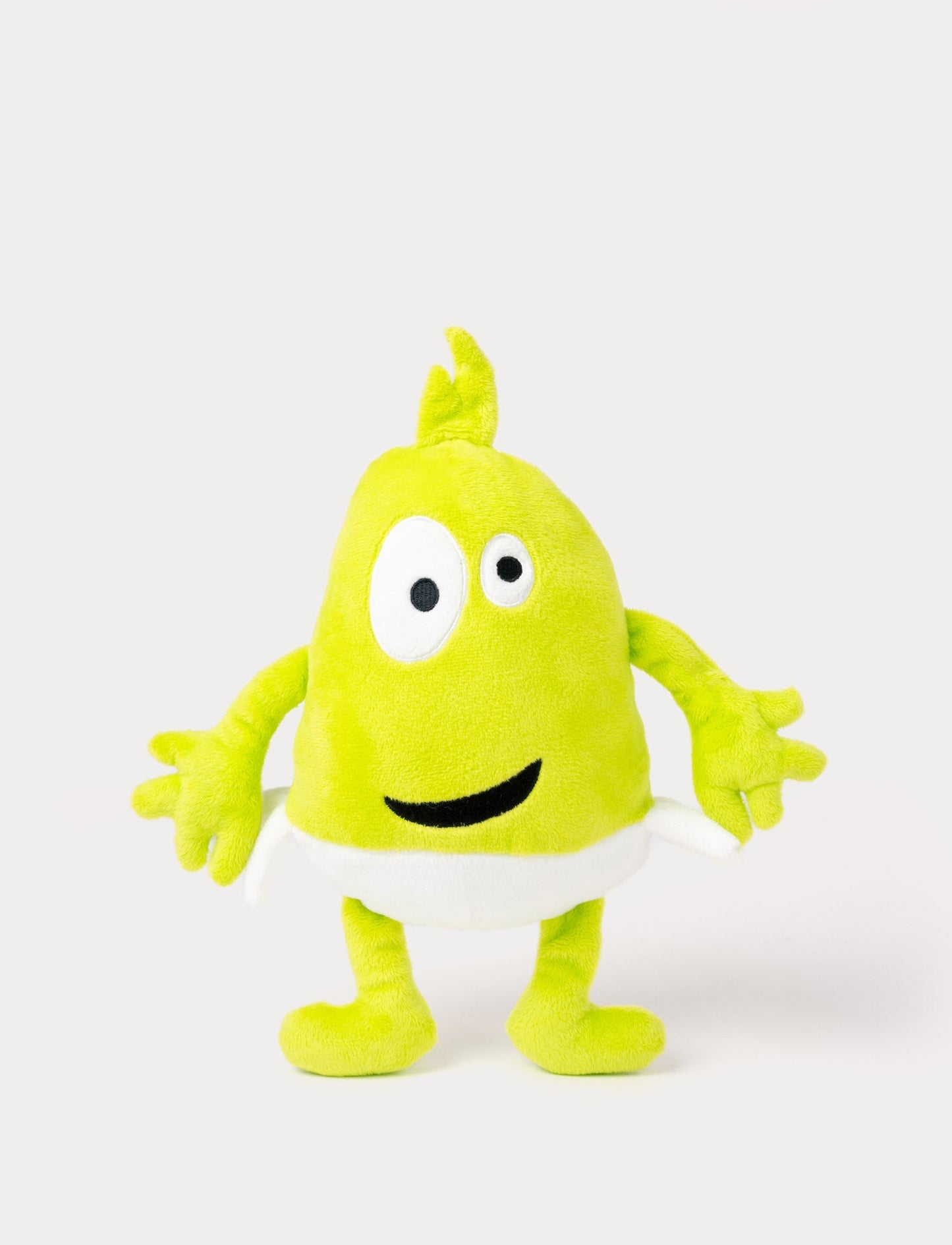 Green plush toy with a tuft on top, large uneven eyes, a wide smile, and a white waistband.