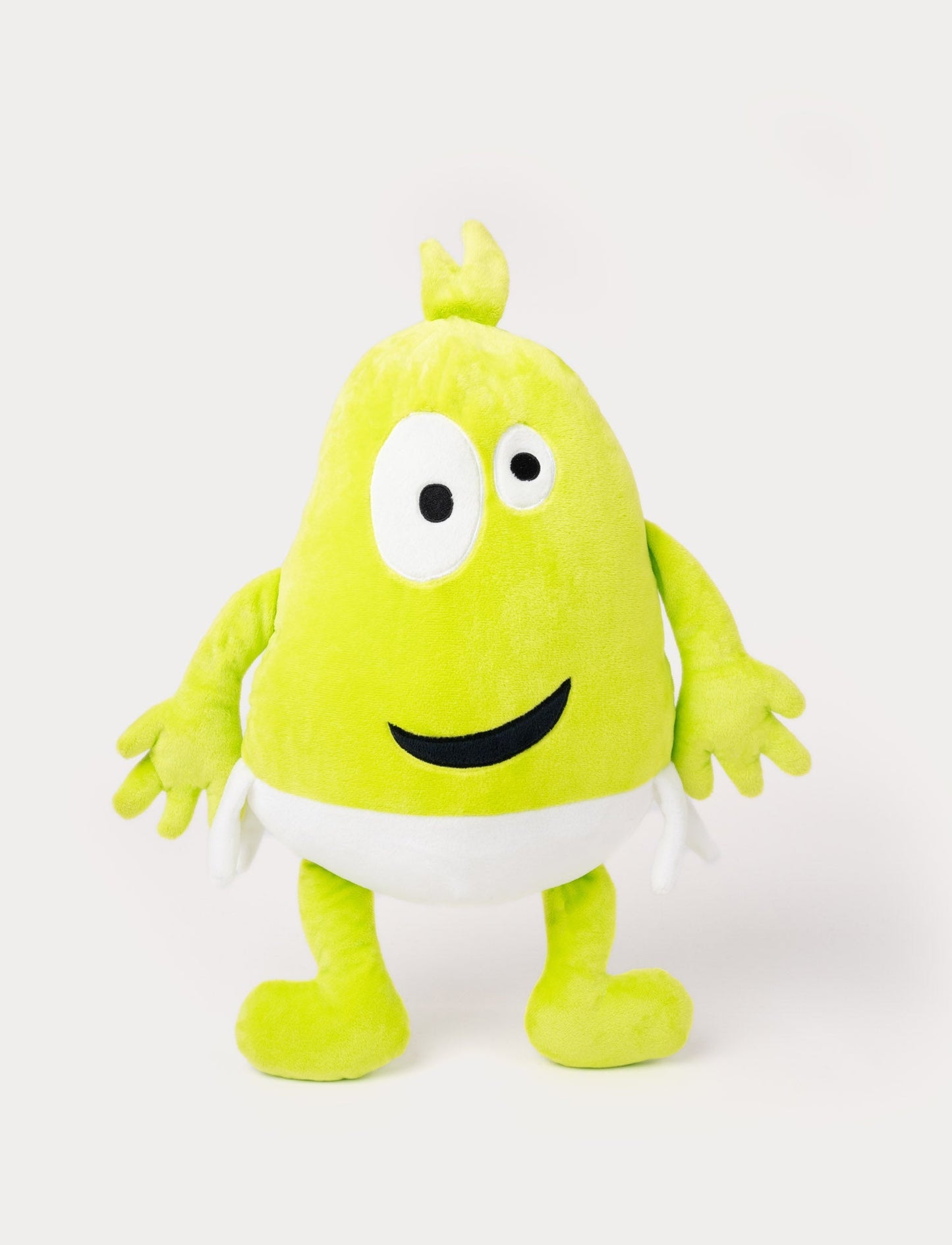 Green plush toy with a tuft on top, large uneven eyes, a playful smile, and a white waistband.