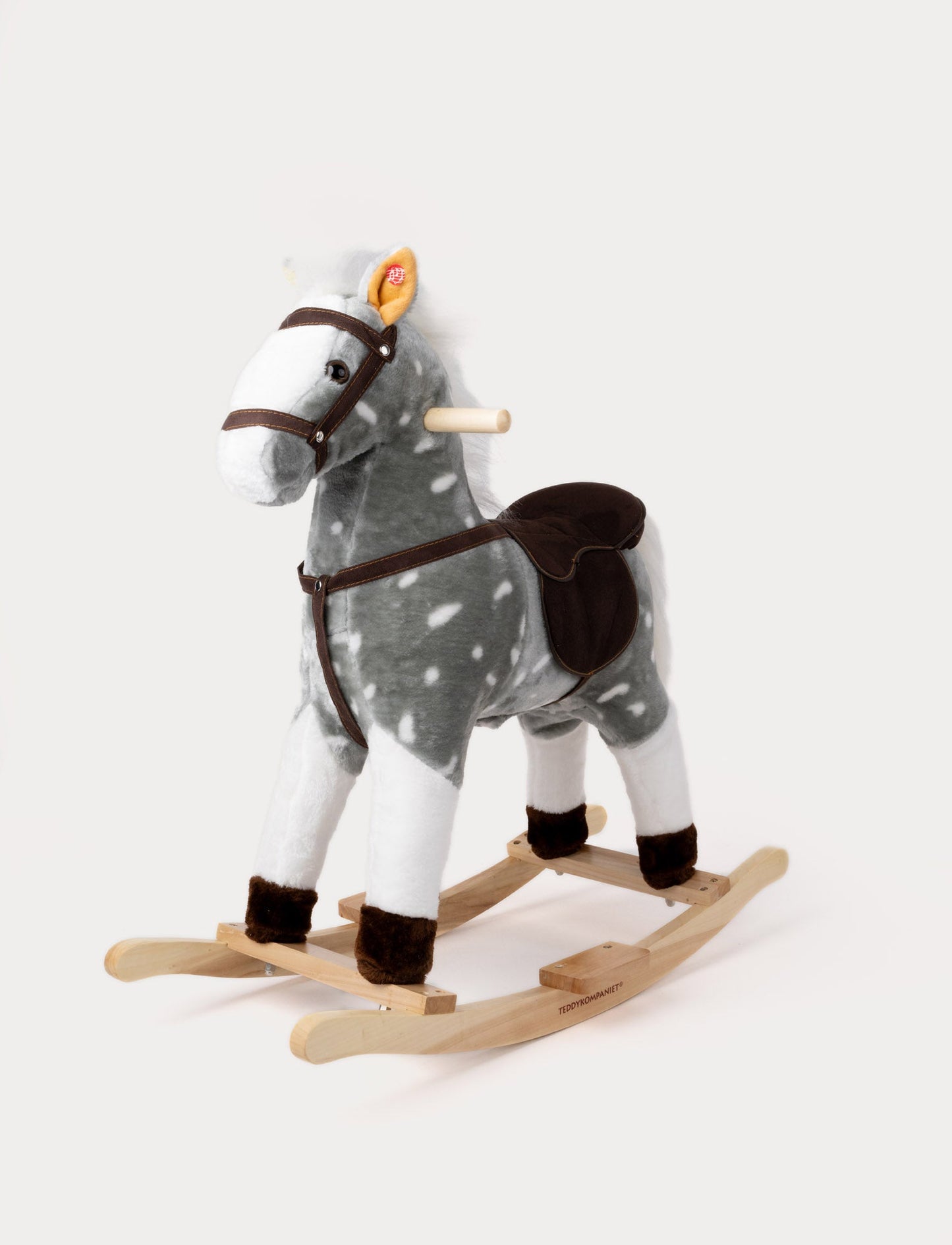 Plush rocking horse with a grey and white spotted coat, brown saddle, and wooden base.
