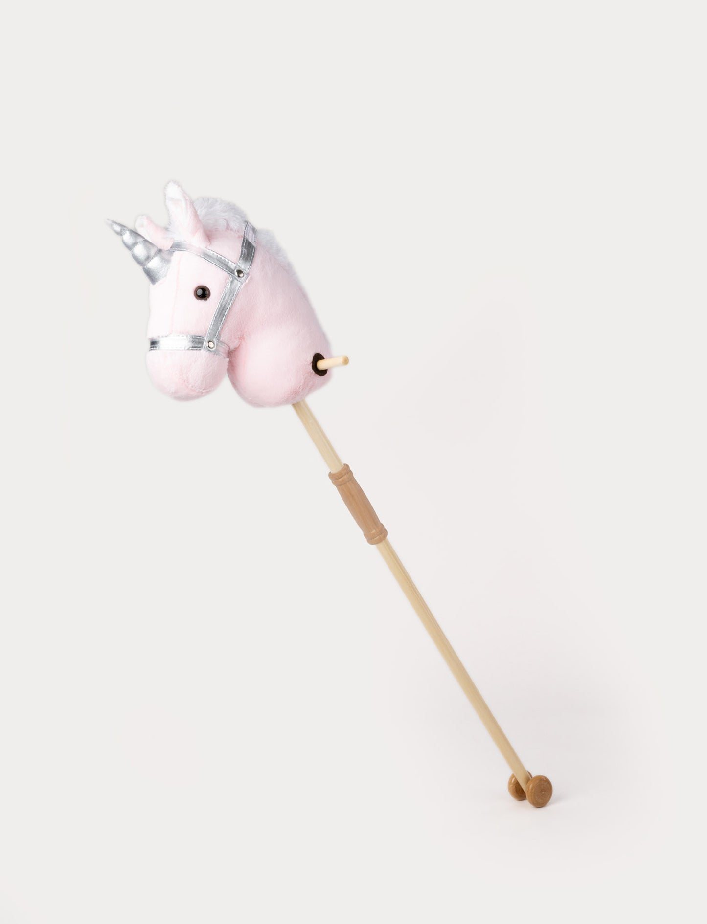Plush hobby unicorn with a soft pink head, silver horn, matching bridle, and a wooden stick with wheels.