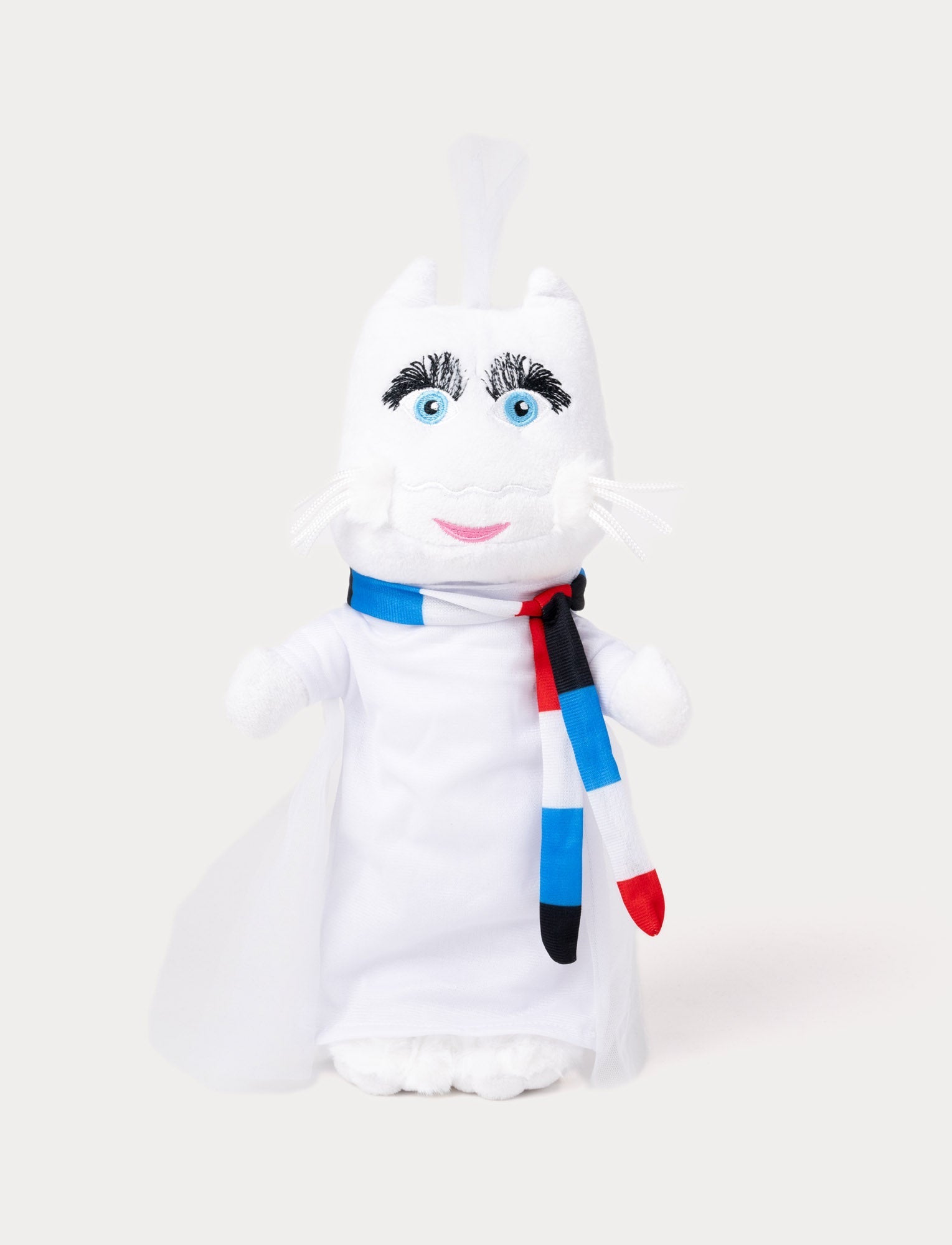  Image of A plush toy of a white cat wearing a flowing cape and a striped red, blue, black, and white scarf.