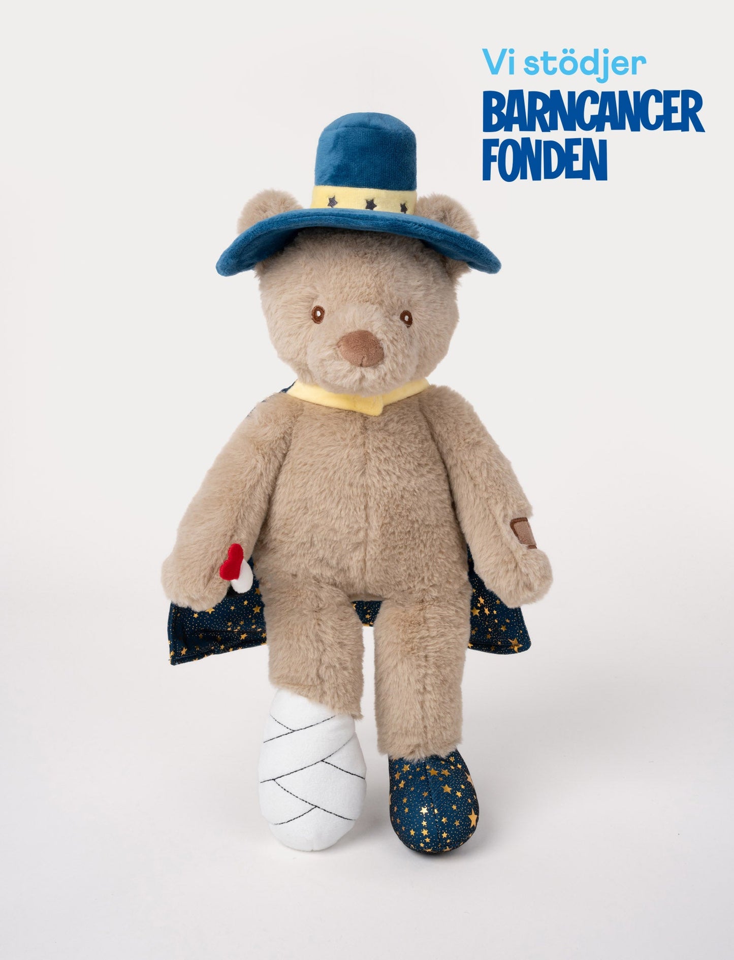 Plush teddy bear dressed as a magician with a blue starry cape, hat, and wand, and one foot wrapped in a bandage.