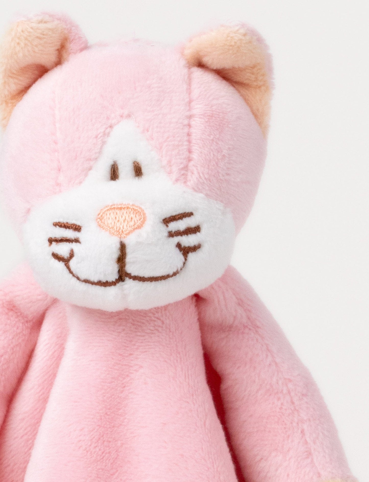 A pink baby blanket with a soft plush cat, white and beige details