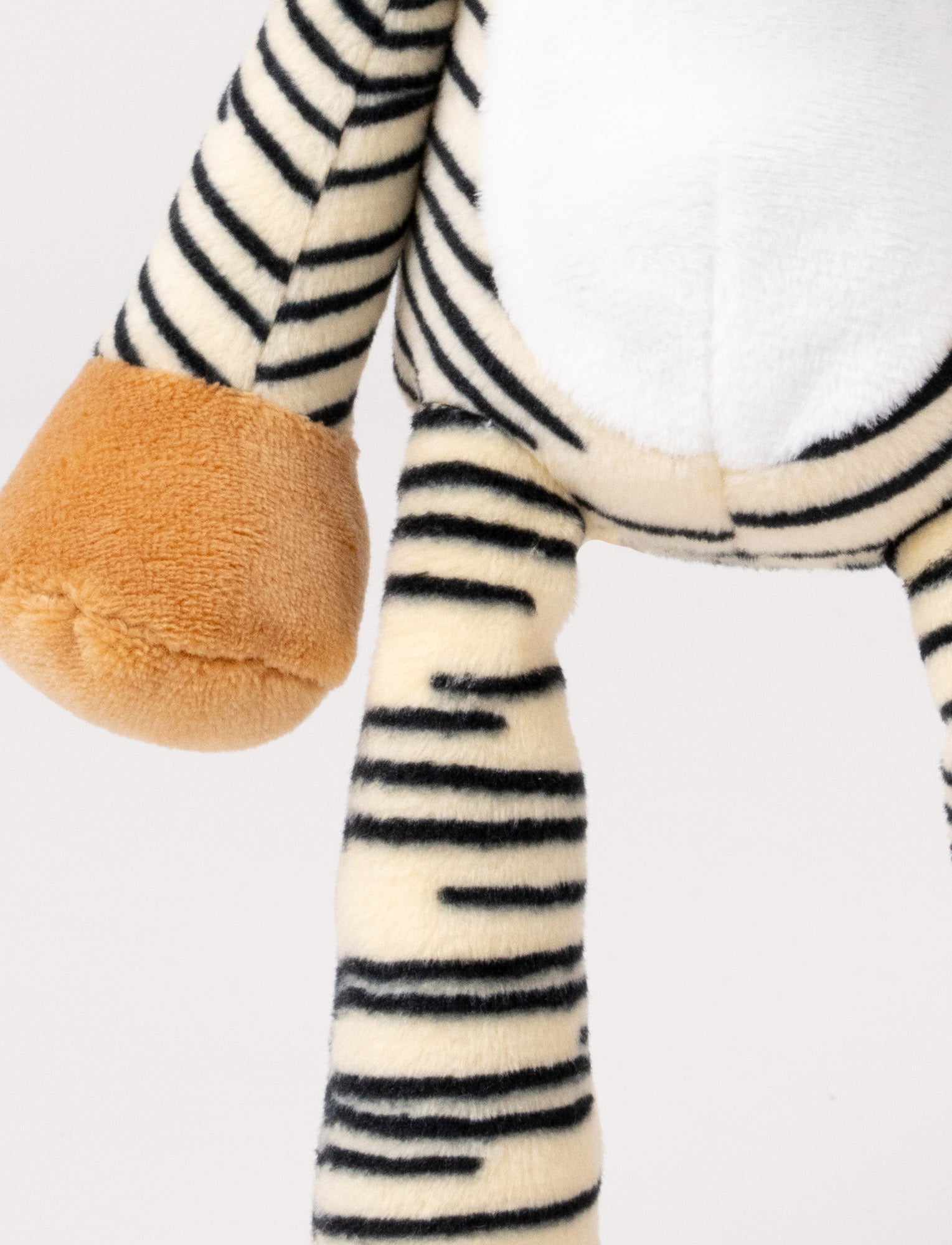  Image of A plush tiger music box with black stripes, a white belly, beige paws, and a fabric loop for hanging