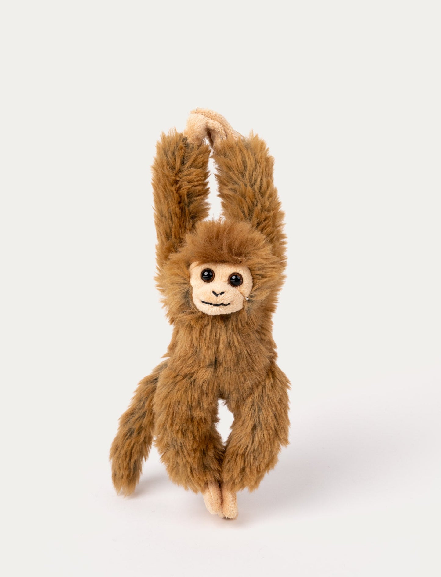 A brown monkey with soft fur, a cheerful smile, and velcro fastenings on its hands and feet.