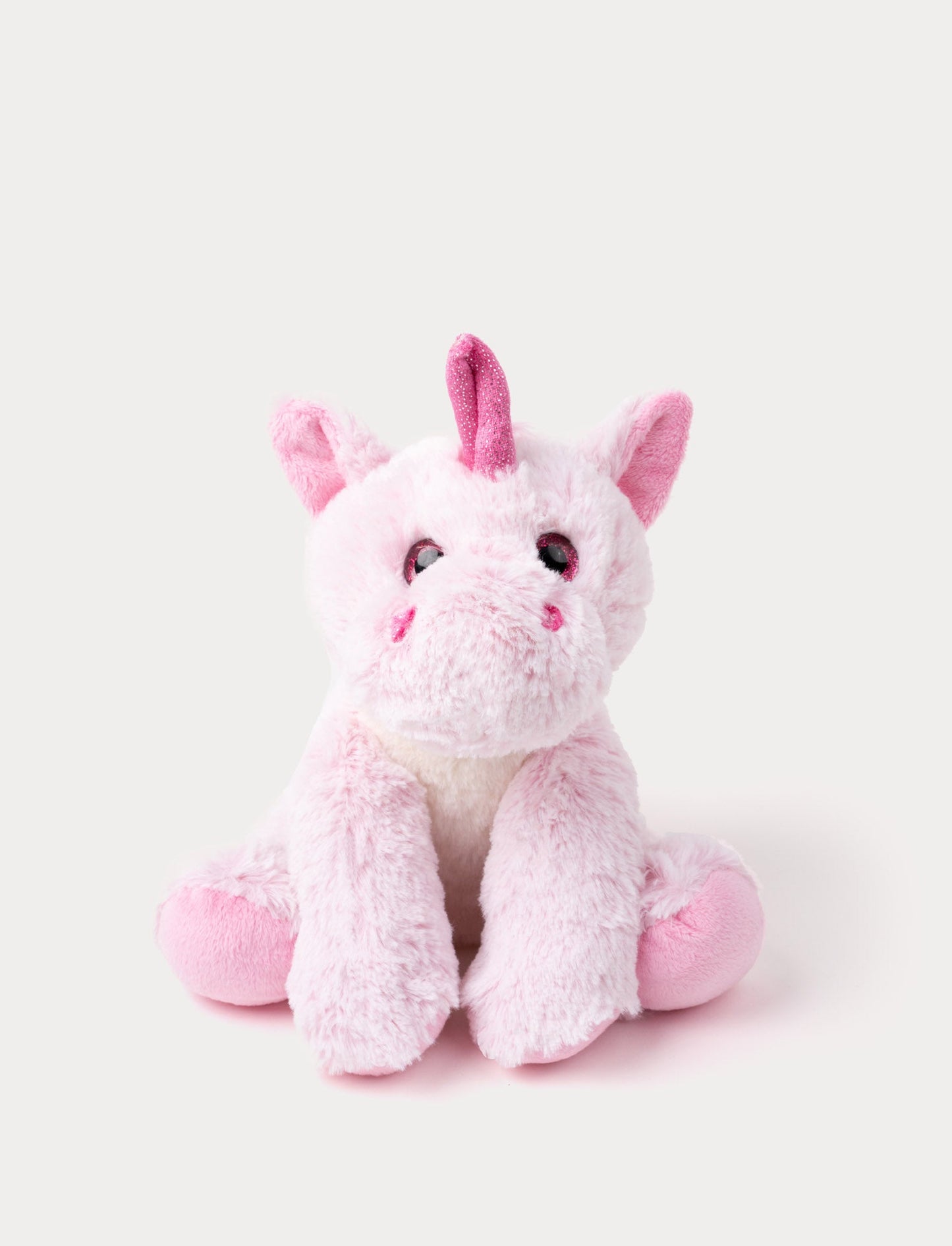 Soft pink plush unicorn with a sparkly horn, round eyes, and floppy legs, sitting upright.