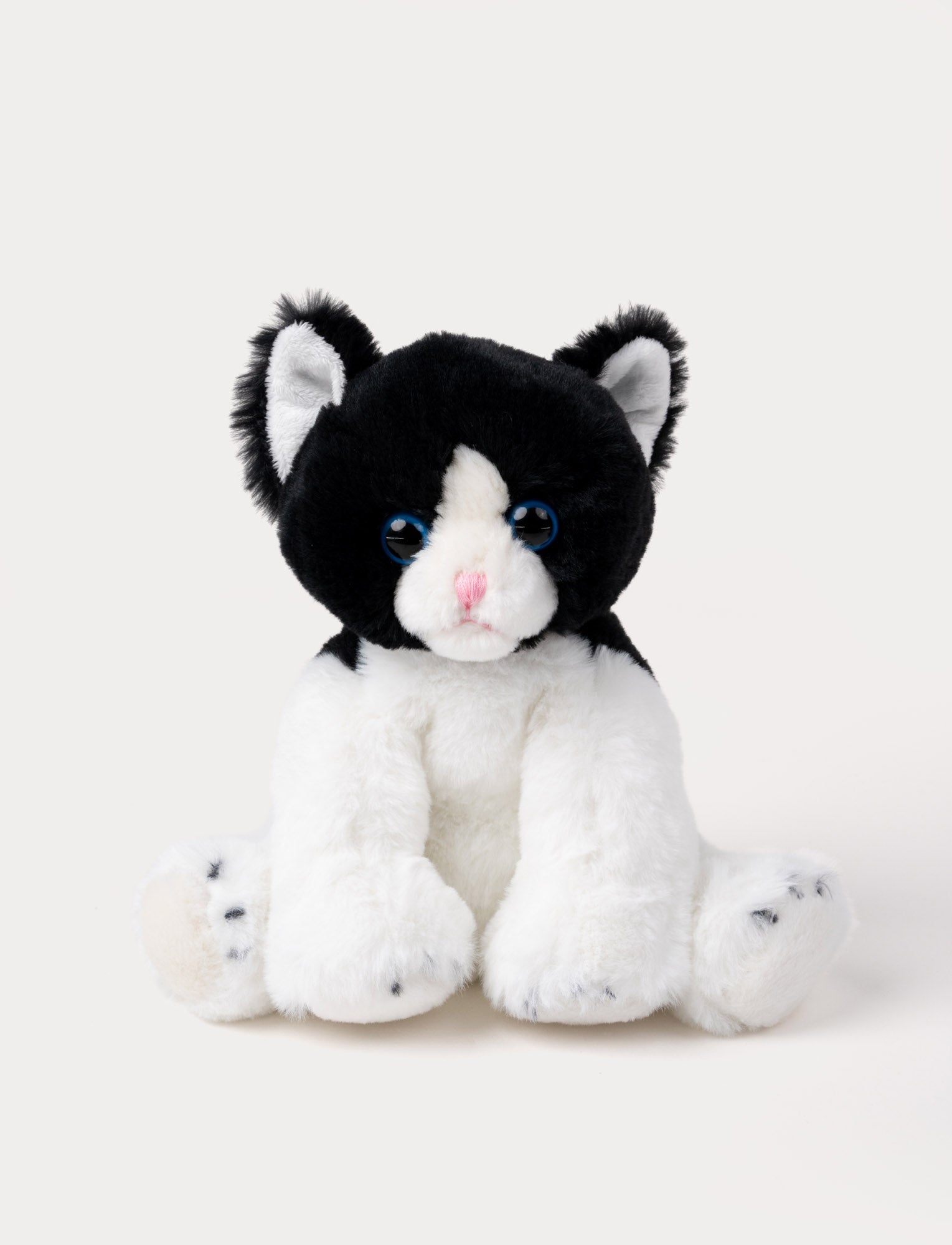  Image of Soft black and white kitten plush with blue eyes, a pink nose, and white paws.