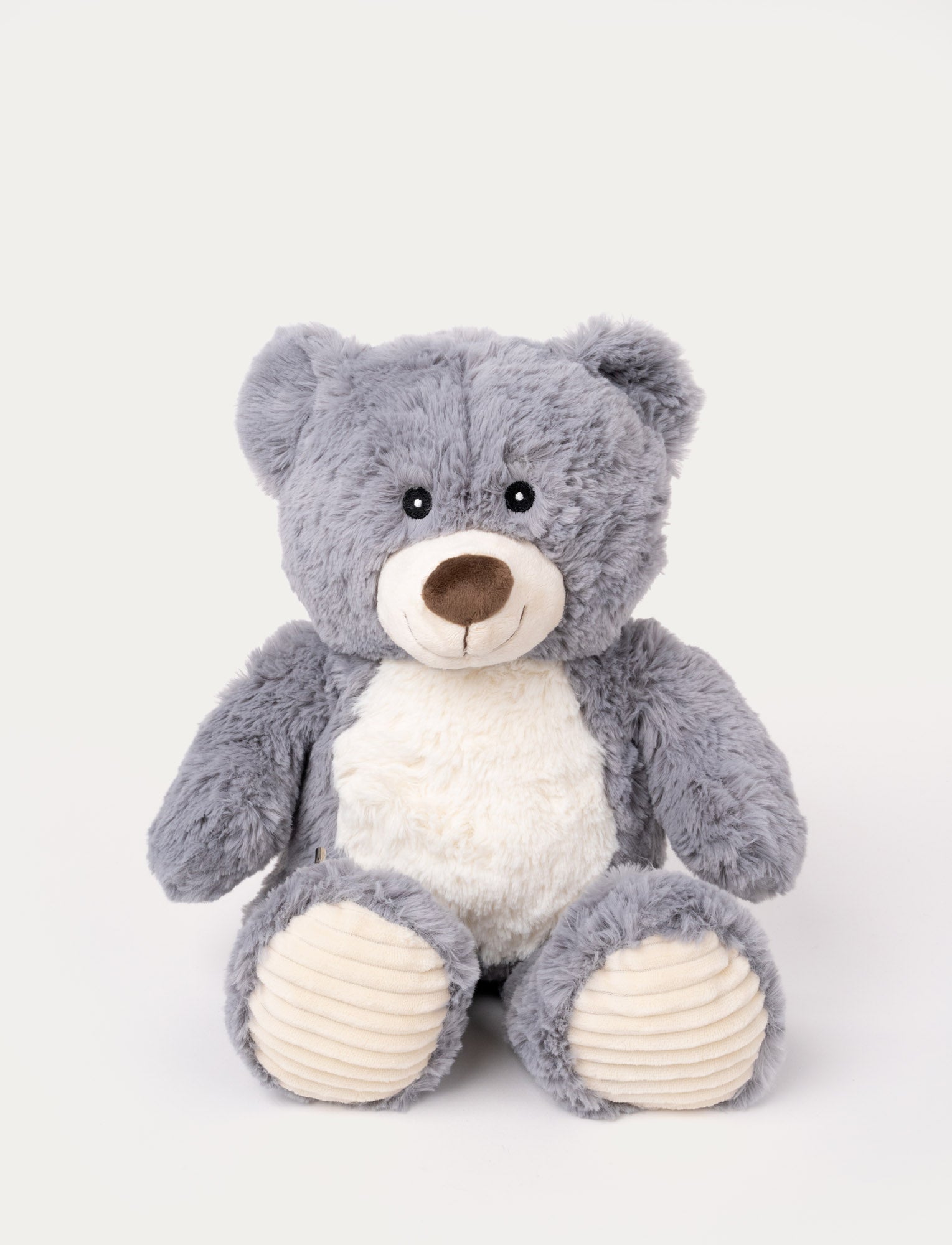  Image of Soft grey teddy bear with a white belly, a stitched smile, and ribbed beige fabric on its paws.