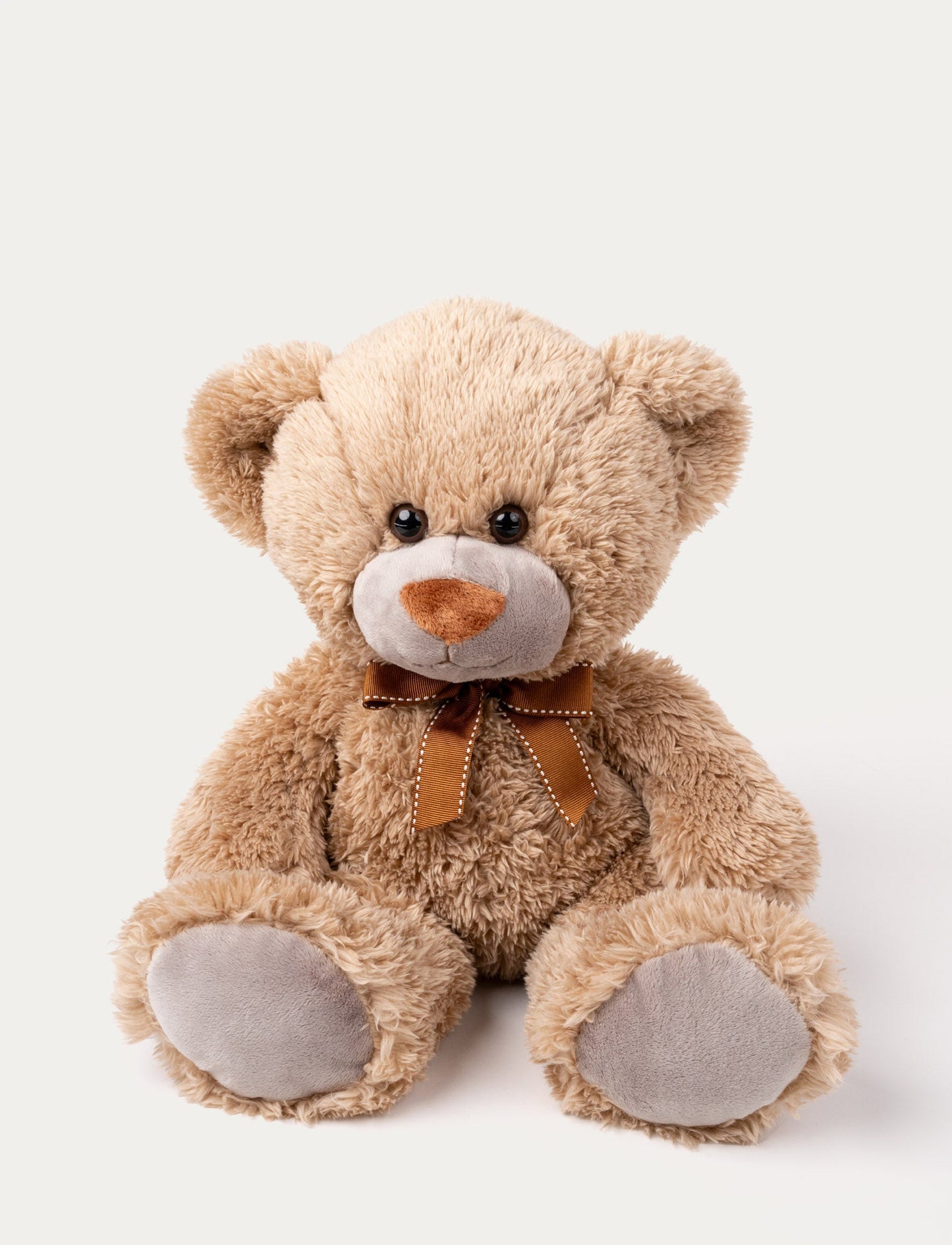 Soft brown teddy bear with grey plush paws, a stitched brown nose, and a brown ribbon with white stitching around its neck.