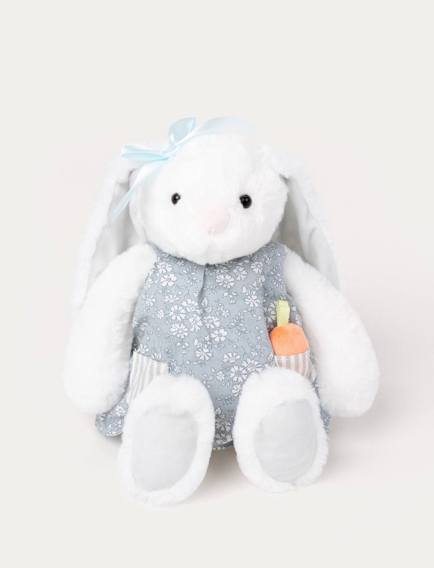 Soft, white plush bunny with long floppy ears, wearing a blue floral dress with a pocket holding a small plush carrot.