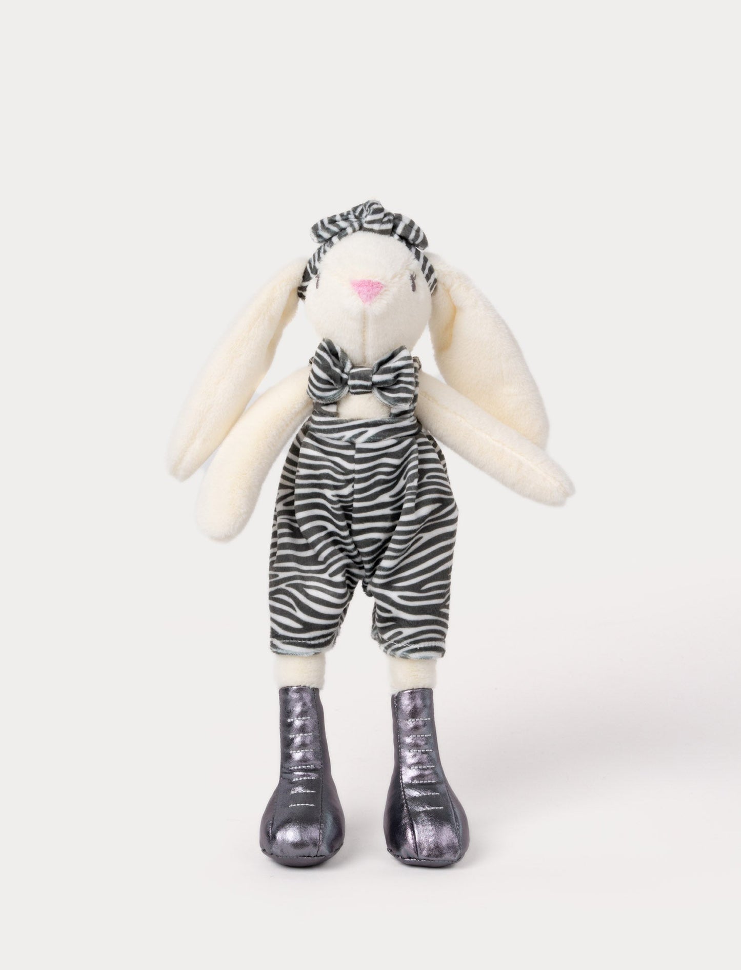 Soft, plush bunny with cream-colored fur, wearing zebra-print overalls, a matching bow, and metallic silver boots.