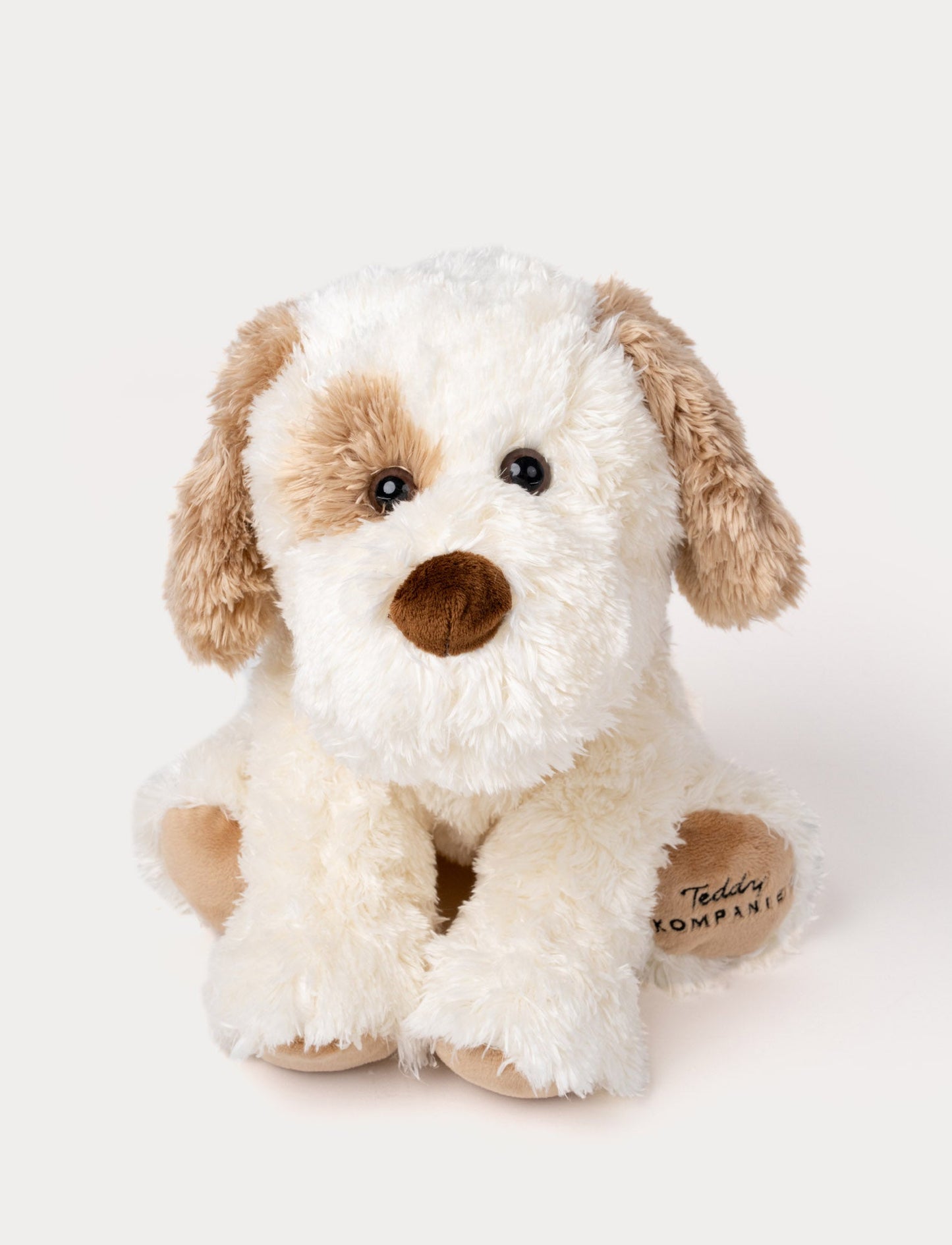 Soft, plush dog with fluffy white and light brown fur, black button eyes, a brown nose, and embroidered text on one paw.