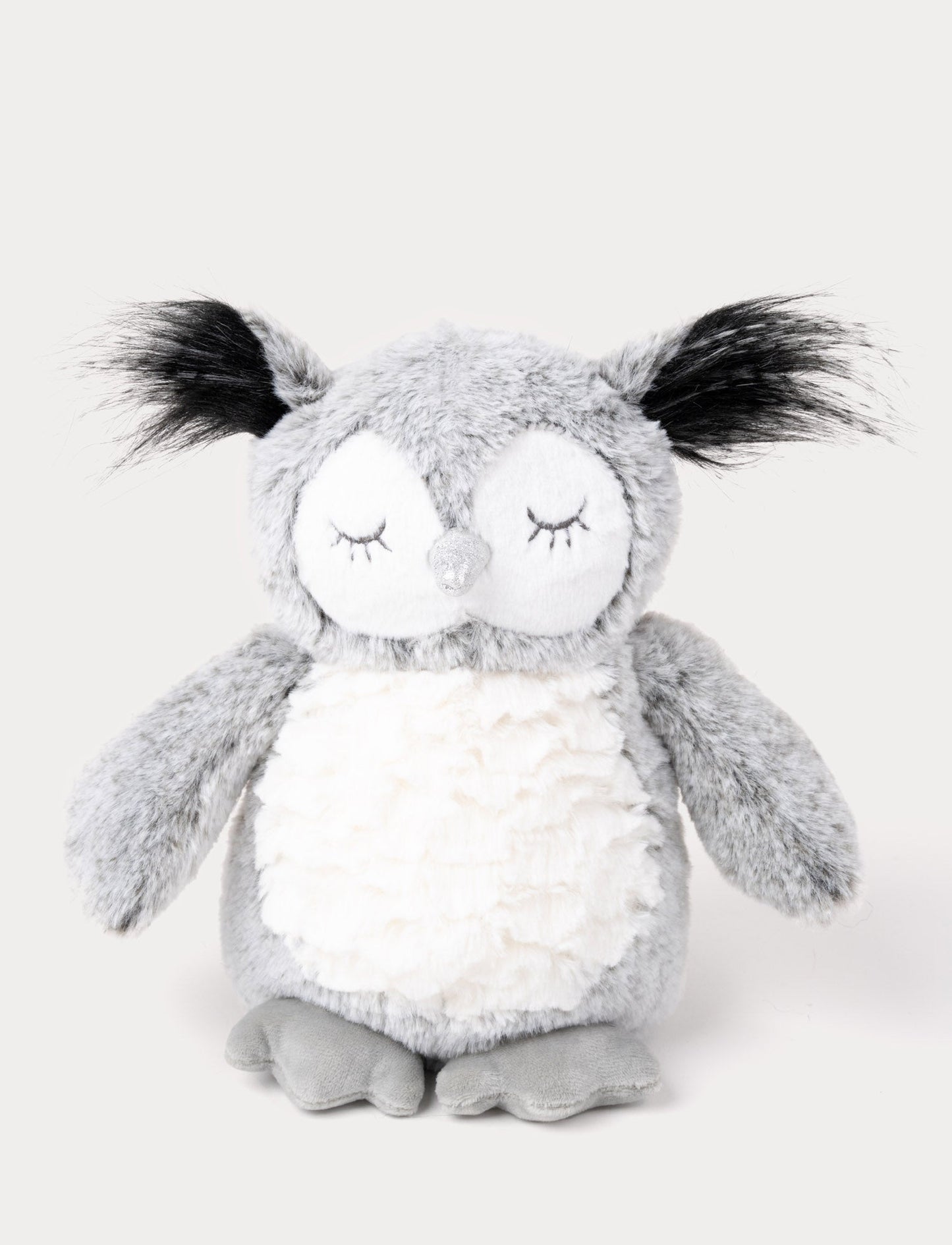 An owl with soft gray fur, a white belly, long ear tufts, and a shimmering silver beak.