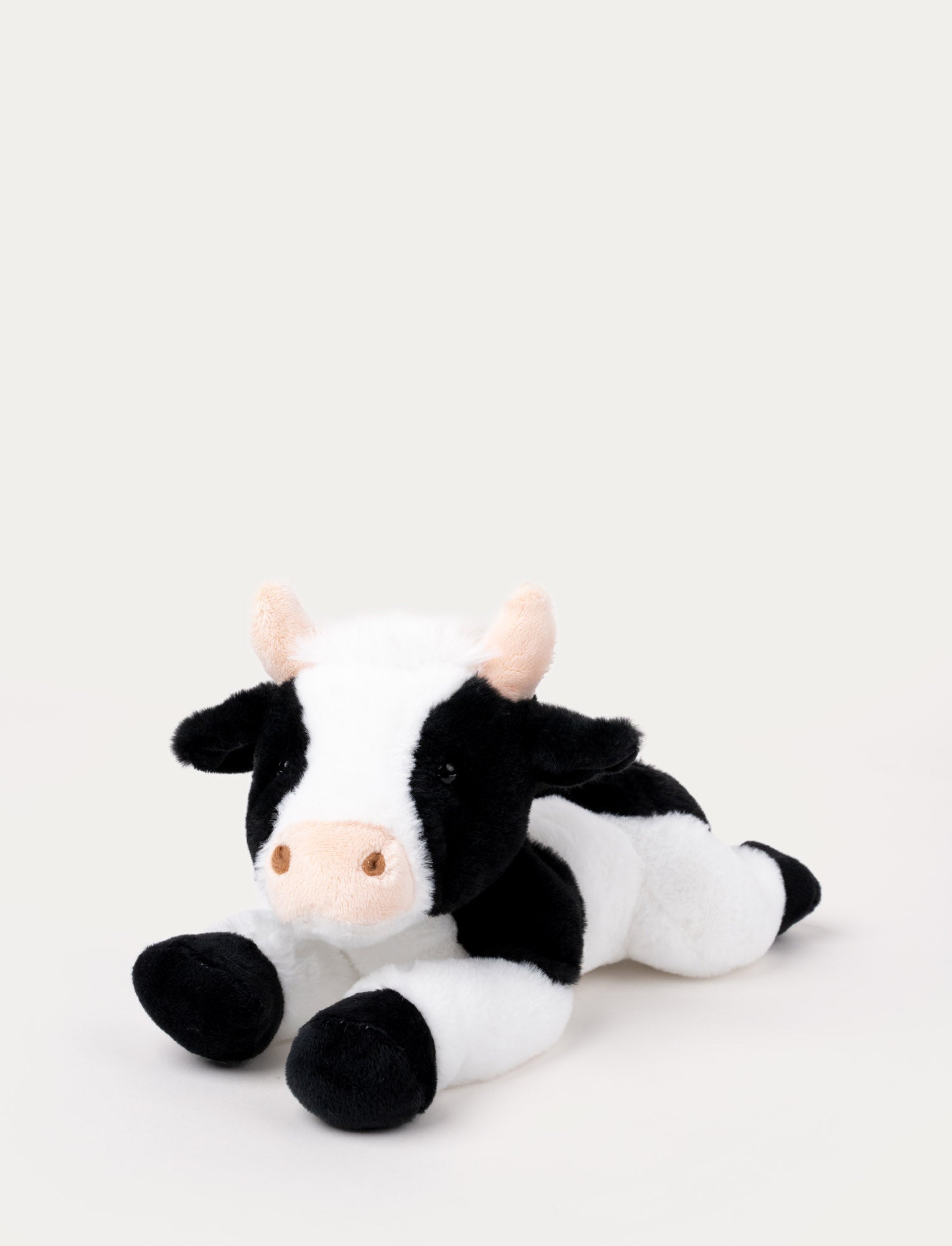  Image of Soft plush cow with black and white fur, a pink snout, and small beige horns, lying down.