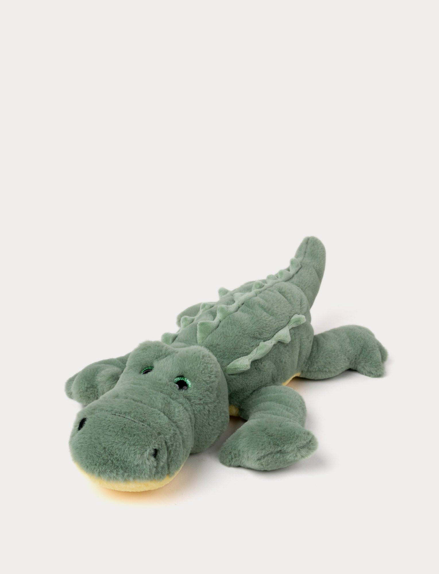  Image of Soft plush alligator with green fur, embroidered eyes, and a textured back, lying down.