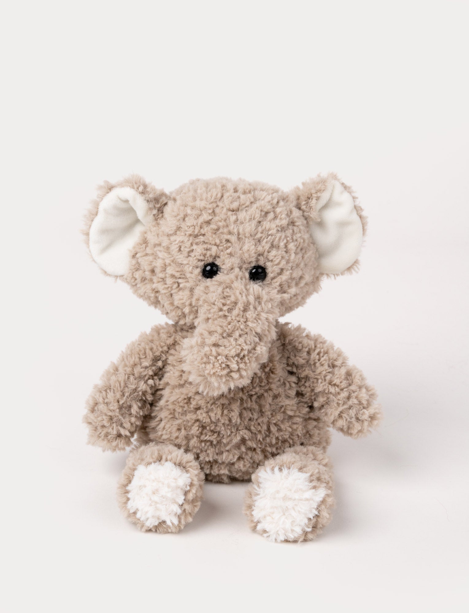  Image of Soft plush elephant in warm grey with a long trunk, white feet, and large floppy ears with white inner lining.