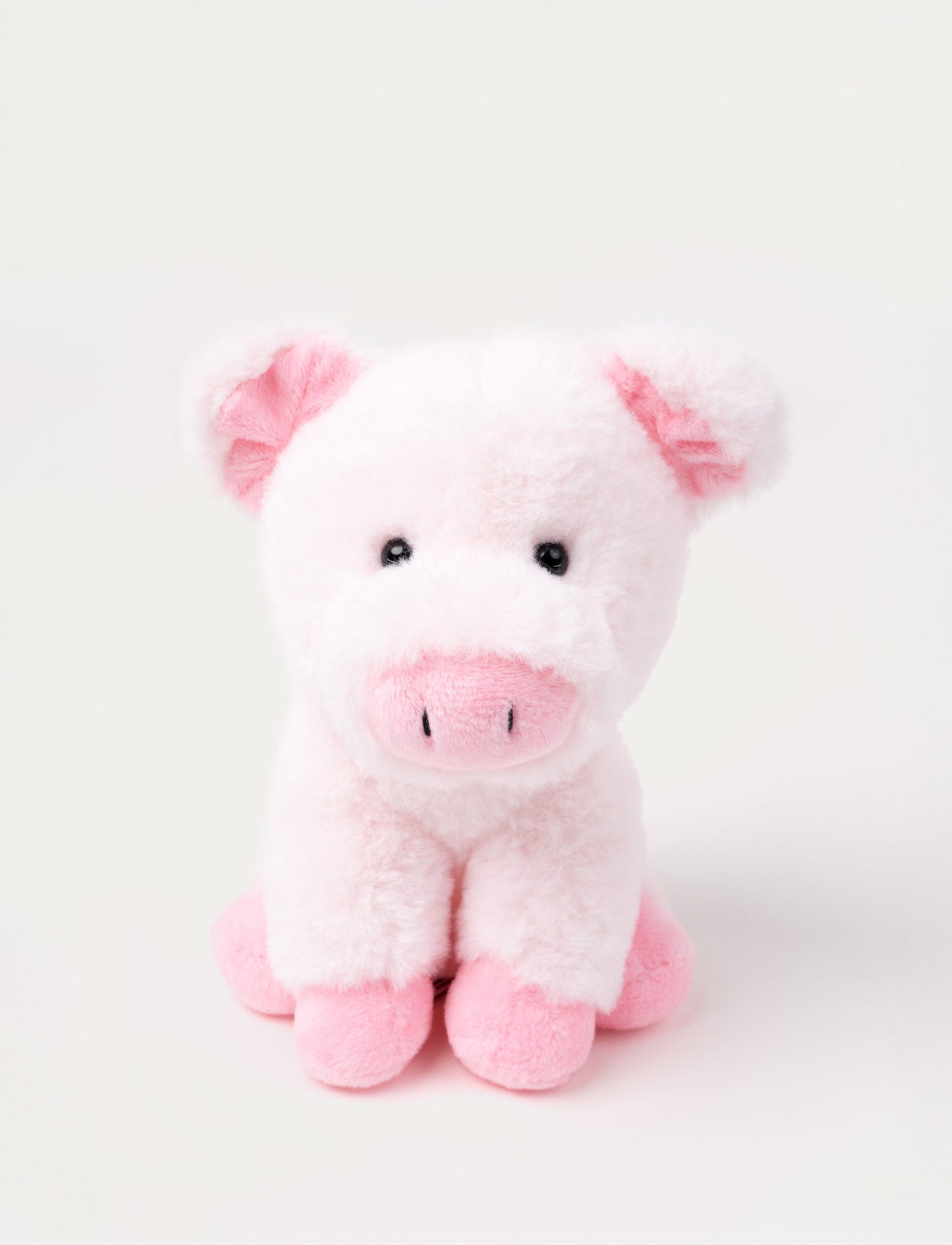 A small pig with light pink soft fur and a gentle expression, sitting in a cozy pose.