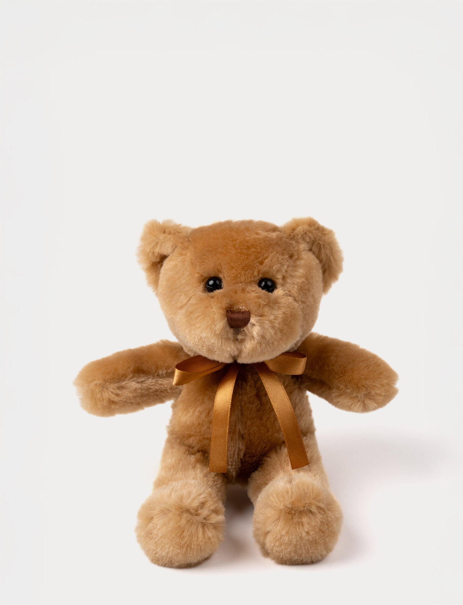  Image of A teddy bear with warm brown fur, an embroidered nose, and an adorable satin bow.