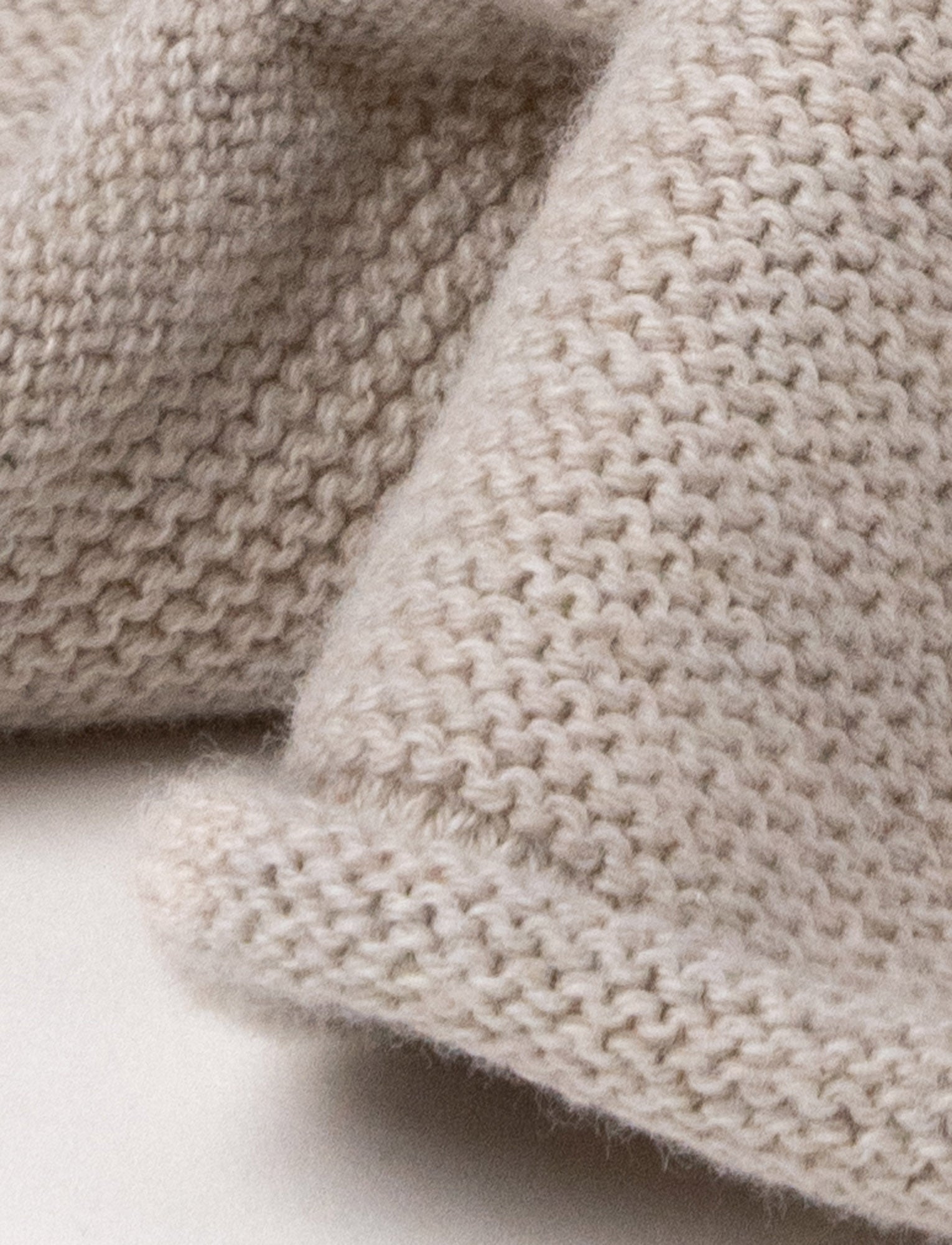  Image of A knitted beige dog comforter with dark floppy ears, a stitched smiling face, and a soft textured fabric.