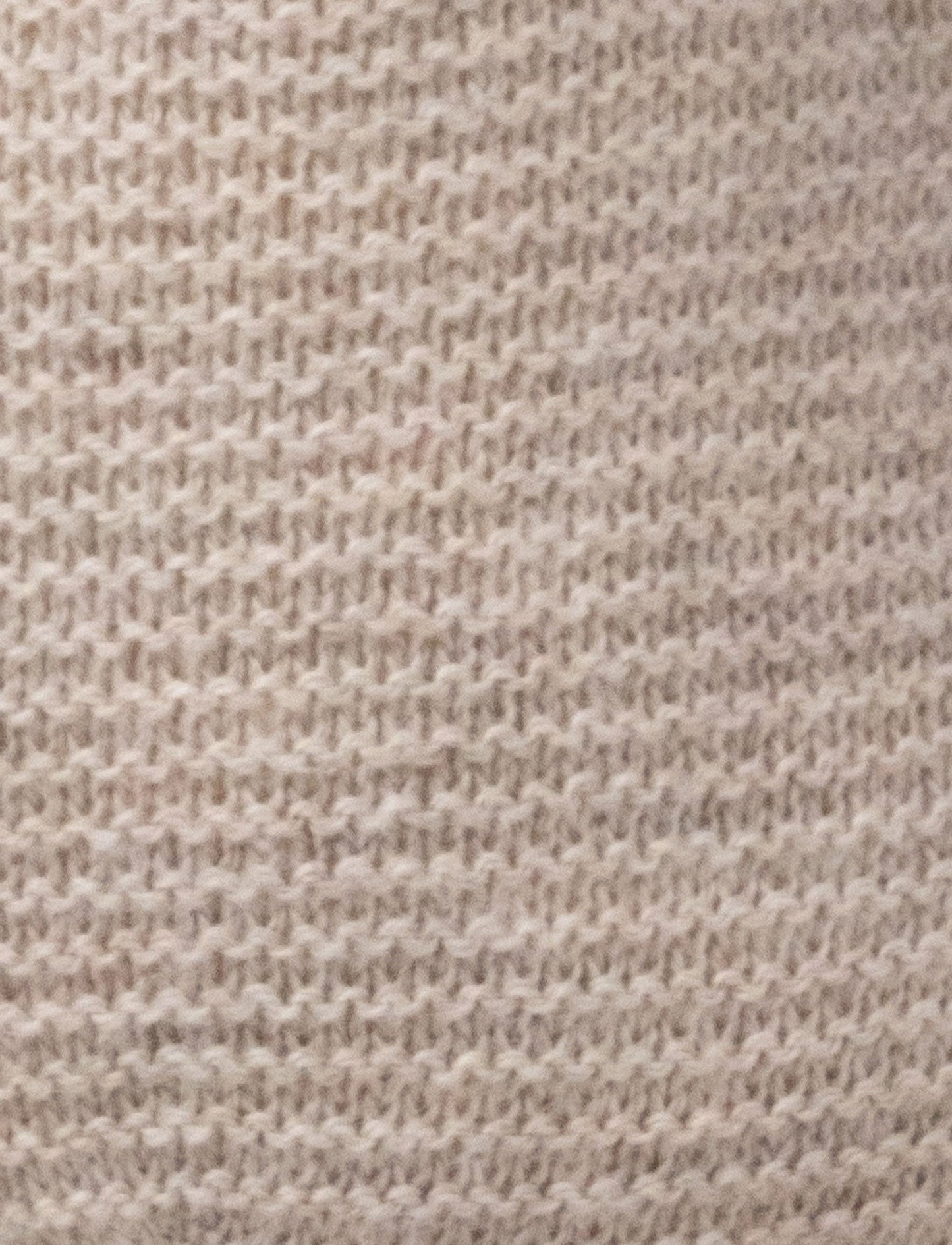 A knitted beige plush dog with dark floppy ears, a stitched smiling face, and a soft textured body.