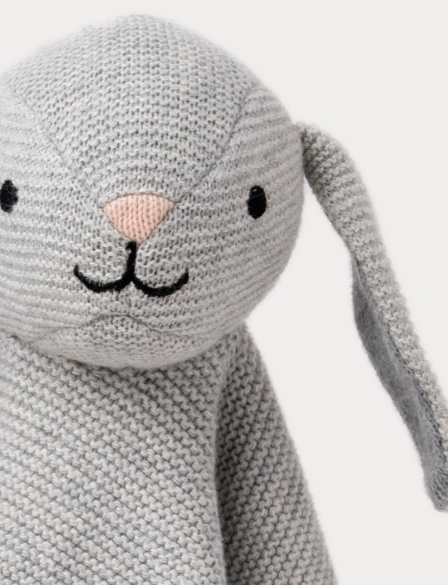 A knitted grey bunny comforter with floppy ears, a stitched face, and a soft textured fabric.
