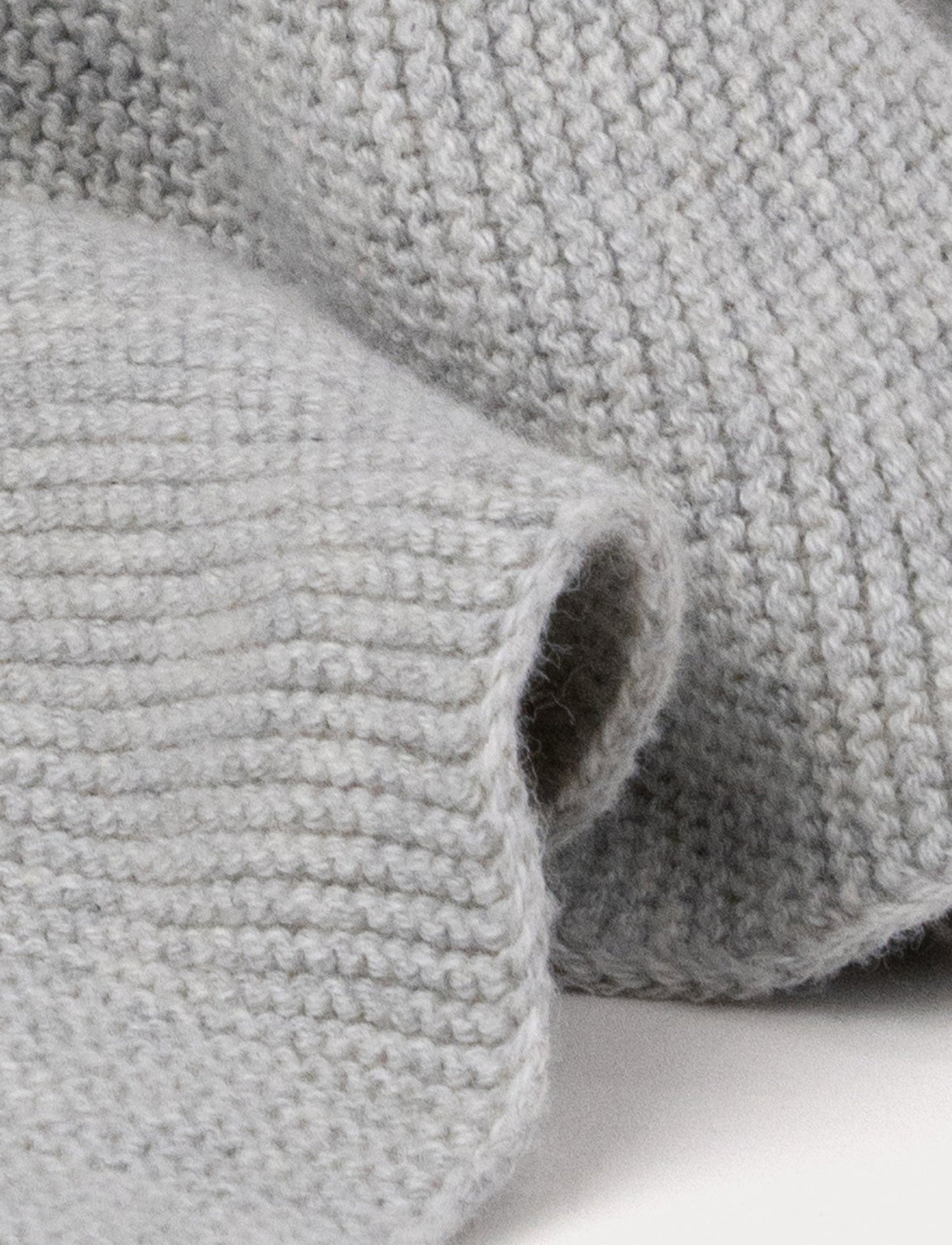 A knitted grey bunny comforter with floppy ears, a stitched face, and a soft textured fabric.