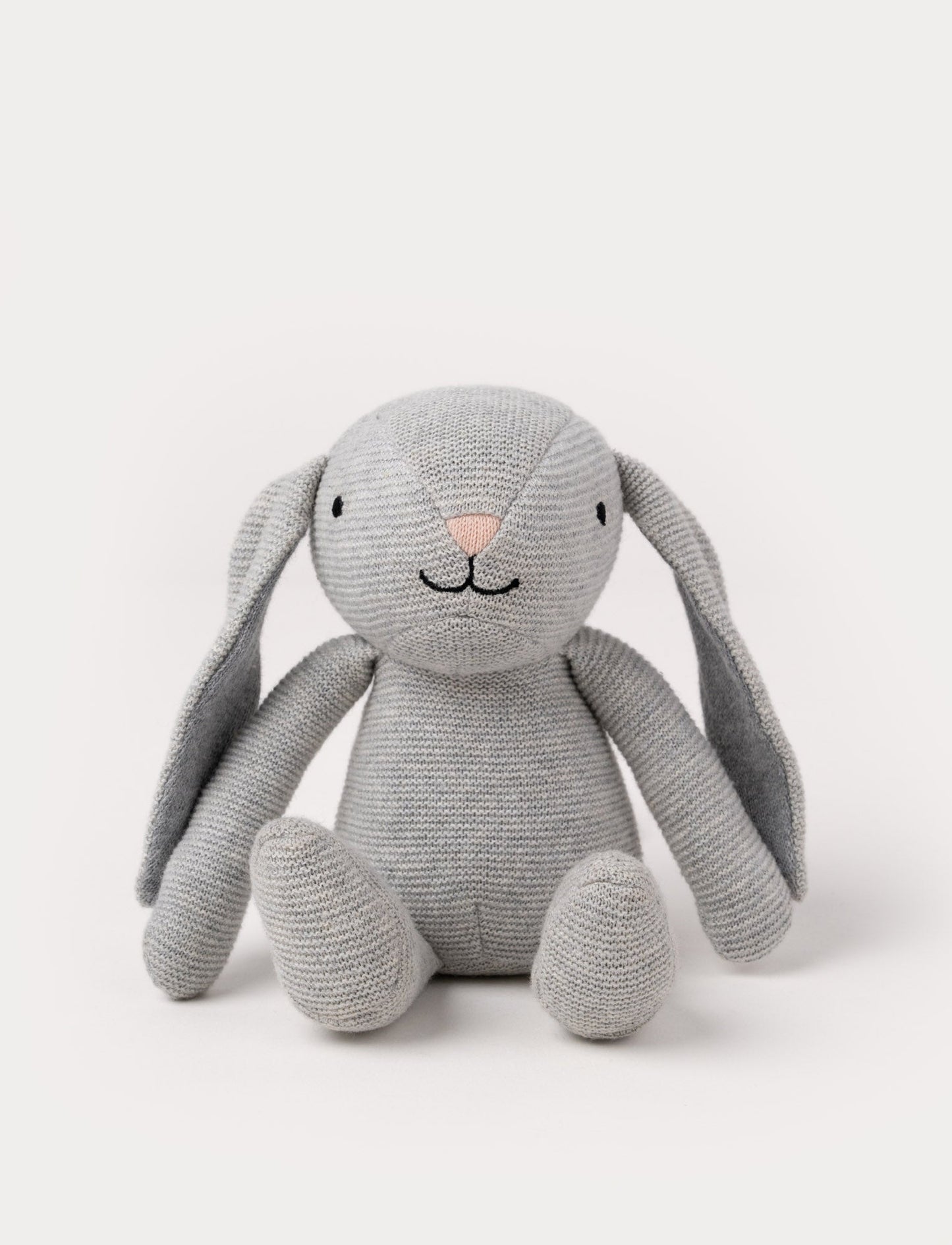 A knitted grey plush bunny with floppy ears, a stitched face, and a soft textured body.