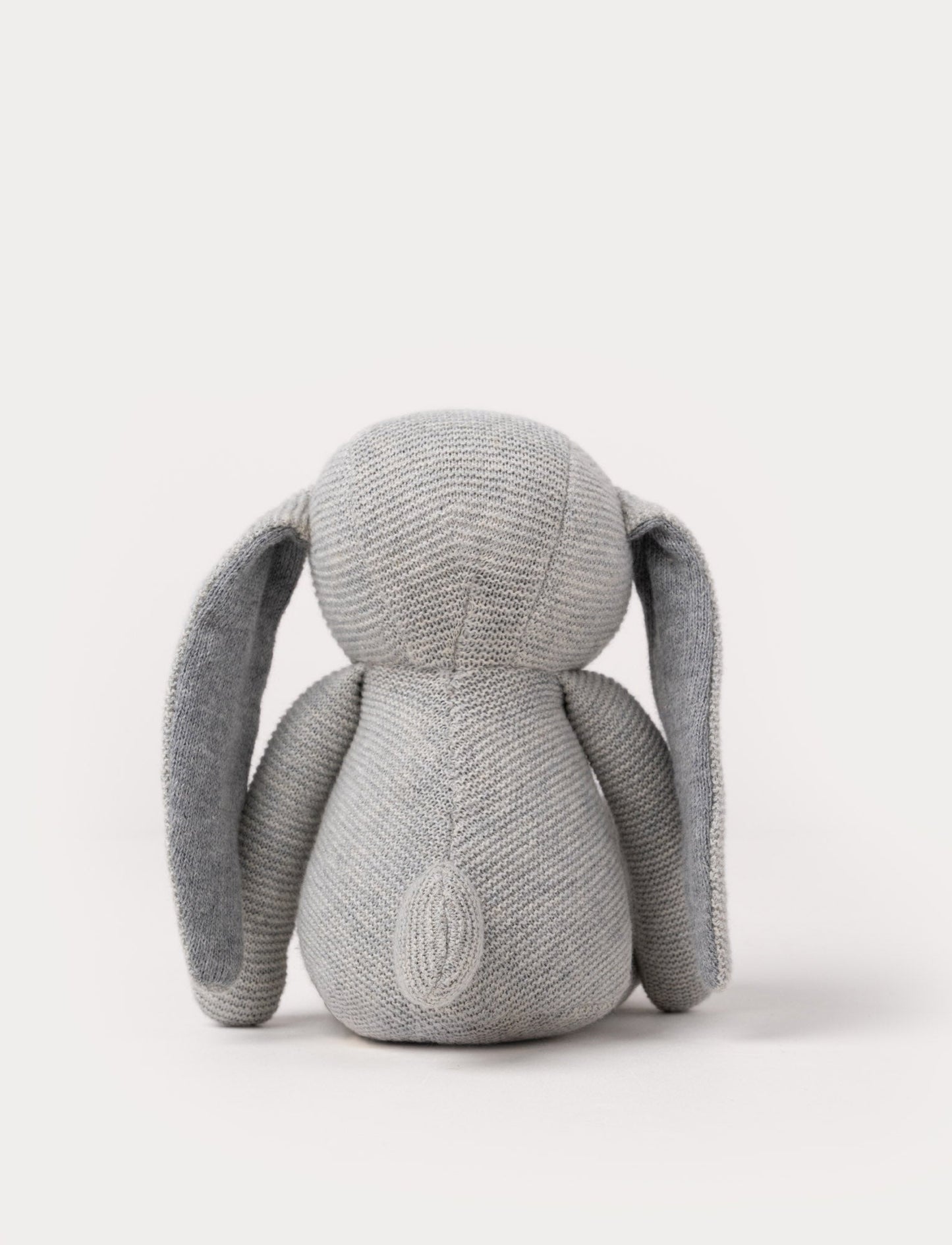 A knitted grey plush bunny with floppy ears, a stitched face, and a soft textured body.
