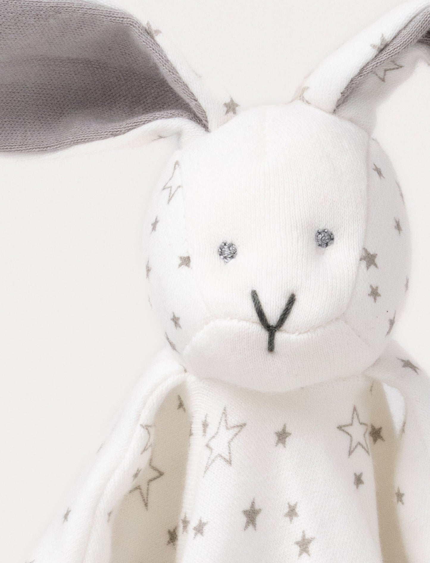 Soft baby blanket with a plush bunny head, long gray ears, and a white star-patterned fabric.