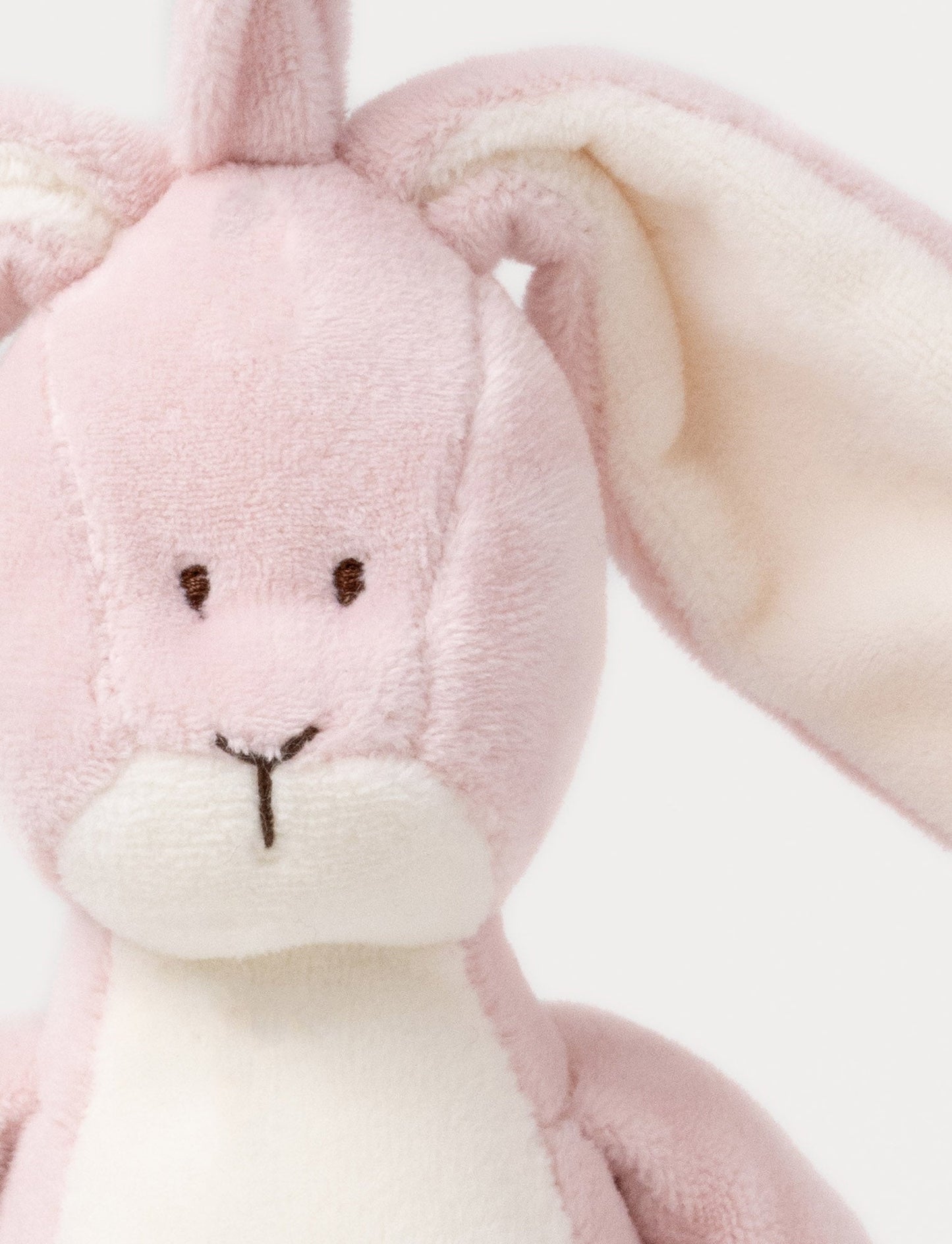 A plush dusty pink bunny music box with long floppy ears, a white belly, and a hanging loop