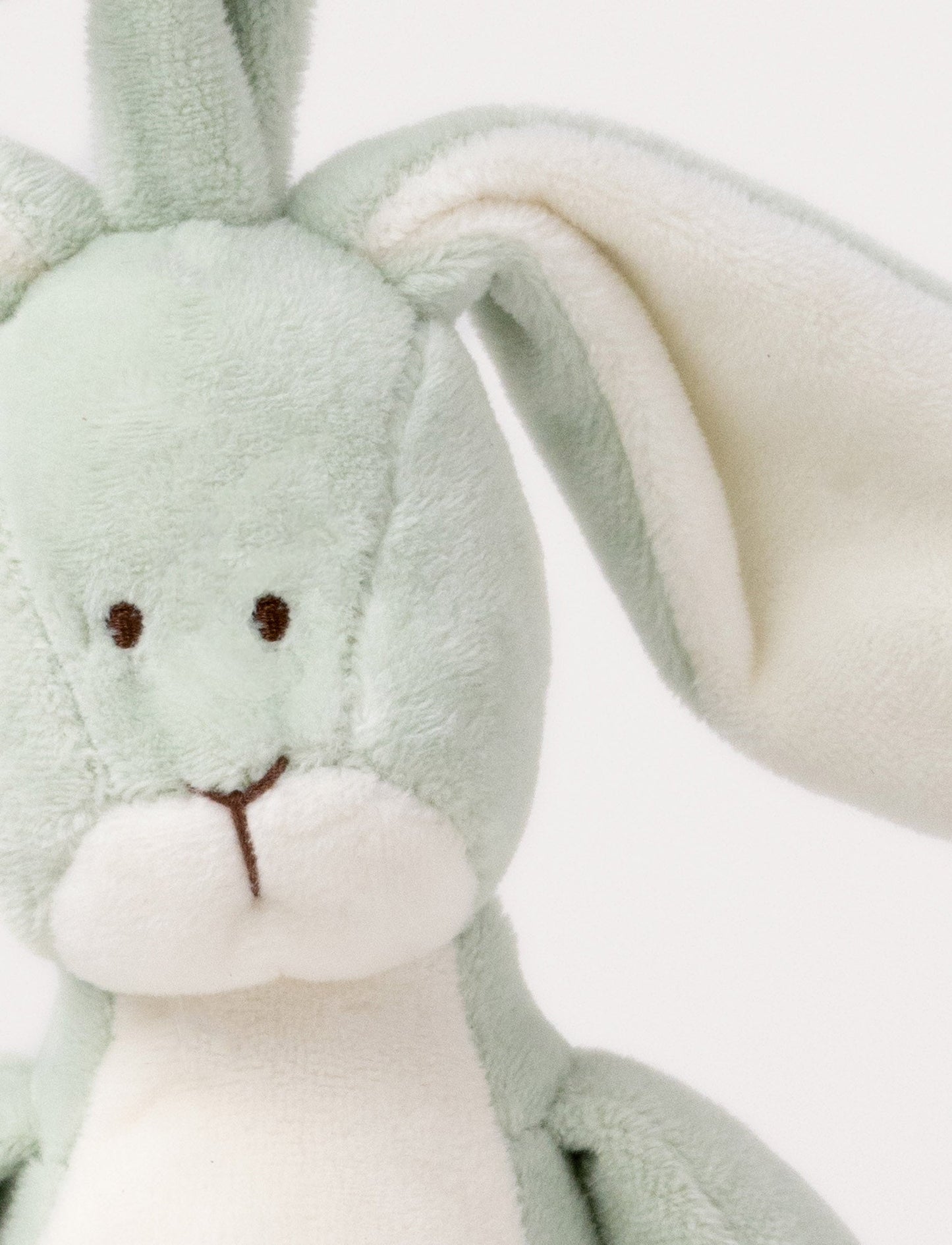 A plush sage green bunny music box with long floppy ears, a white belly, and a hanging loop.