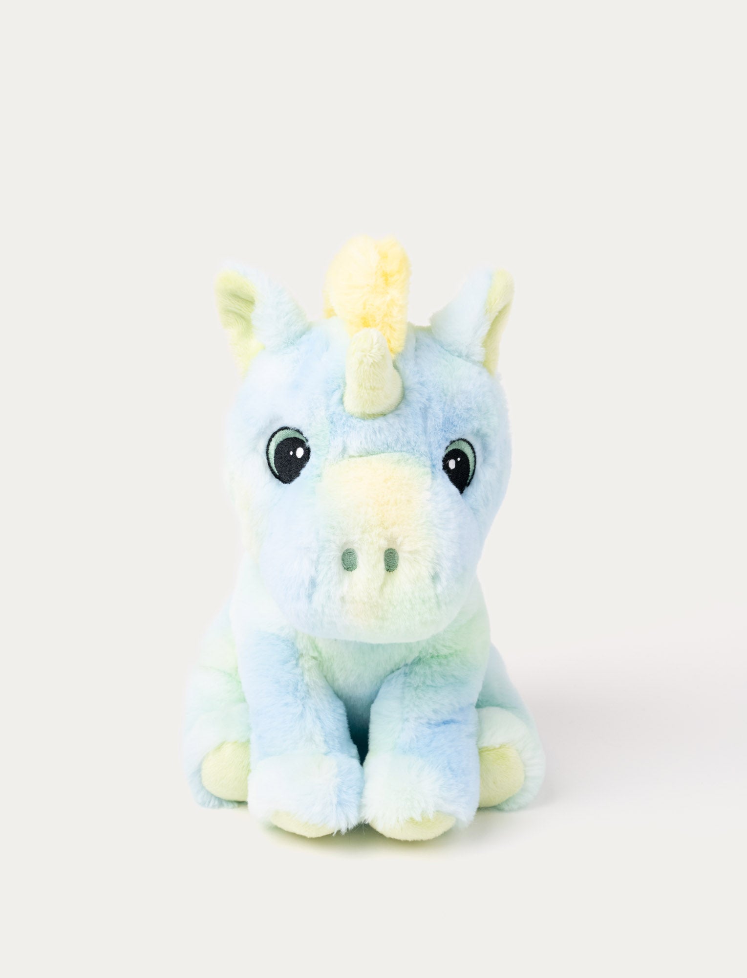  Image of A pastel rainbow unicorn with soft fur, embroidered eyes, yellow, blue, & green shades.