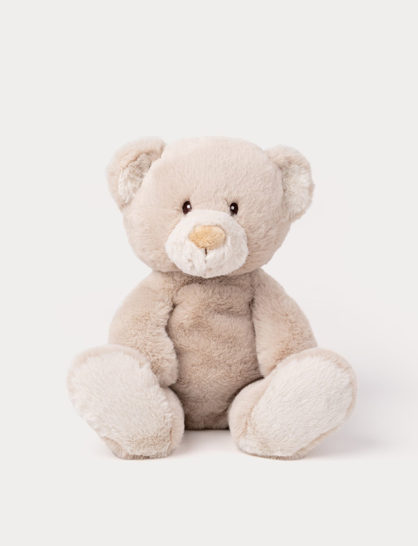 A beige teddy bear with soft fur, faux suede detail on its back, and embroidered eyes.