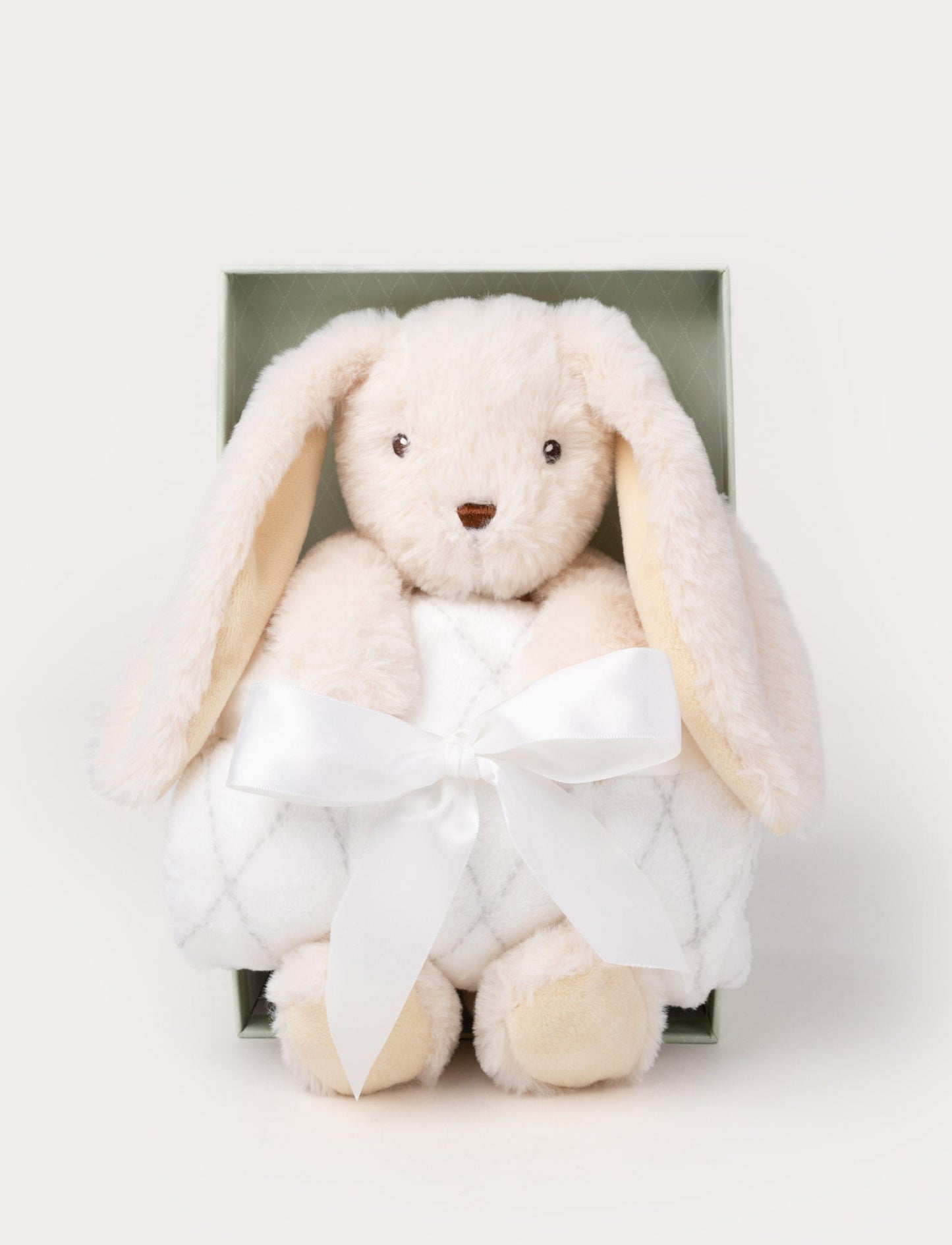 Gift set with a cream-colored plush bunny holding a soft white blanket tied with a satin ribbon, presented in a green box.