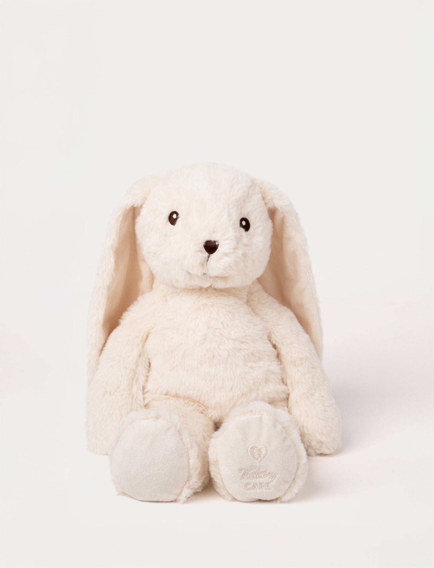 Soft cream-colored bunny plush with long floppy ears, embroidered eyes, and "Teddy CARE" stitched on one paw.